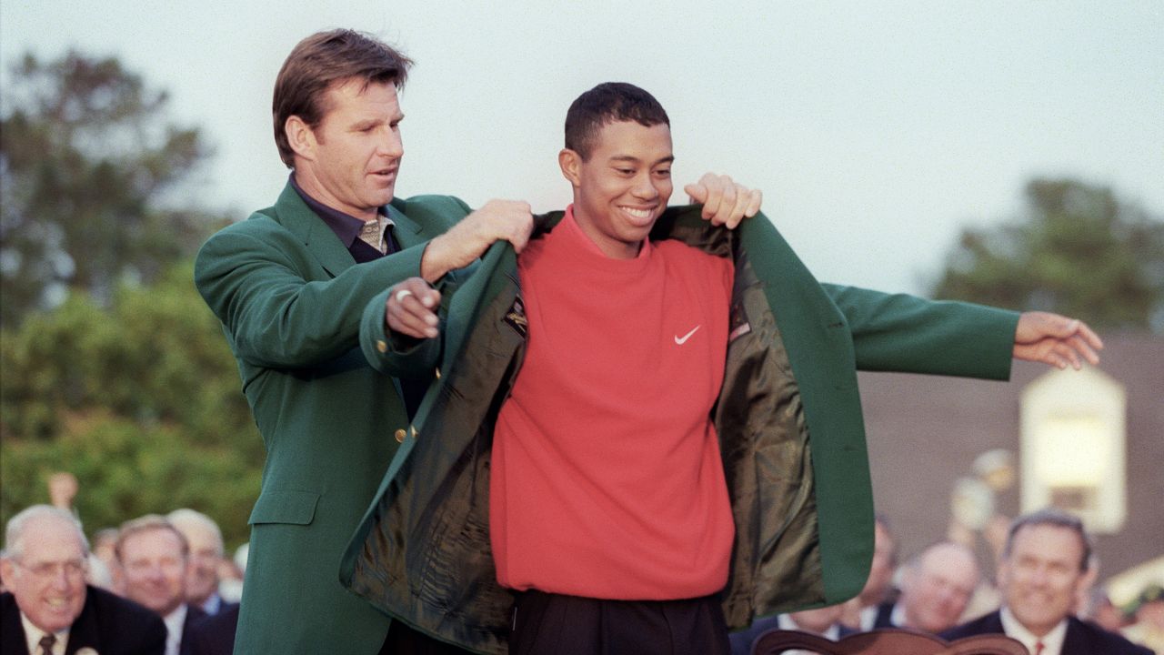 Faldo helps 1997 Masters champion Woods into his green jacket.