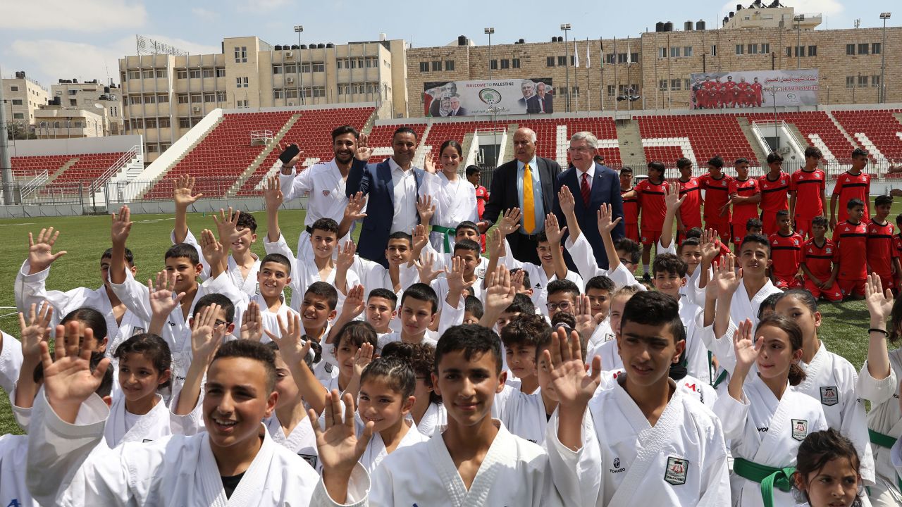 International Olympic Committee President Thomas Bach, back right, and President of the Palestine Olympic Committee Jibril Rajoub, second right, back, meet with young Palestinian athletes at Faisal Al-Husseini stadium in the West Bank city of Al-Ram, north of Jerusalem, in September 2022.