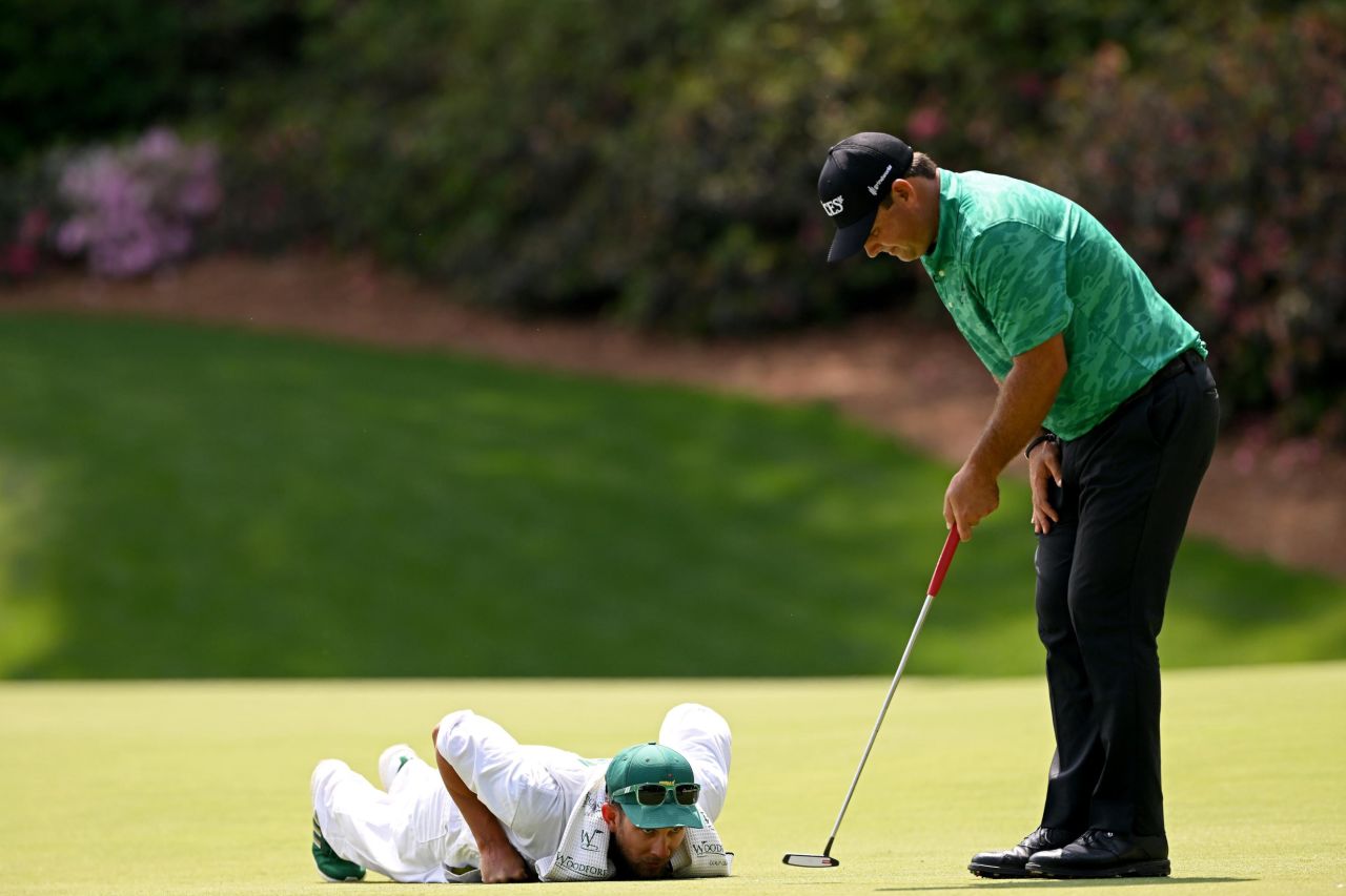Patrick Reed's caddie, Kessler Karain, helps Reed line up a putt on the 13th hole Thursday.