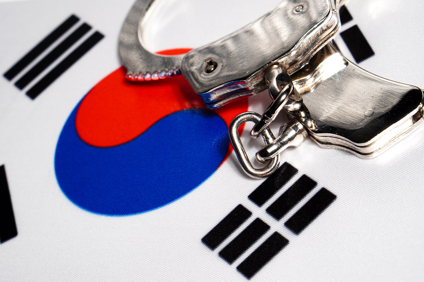 A set of handcuffs rest on a representation of the flag of South Korea.