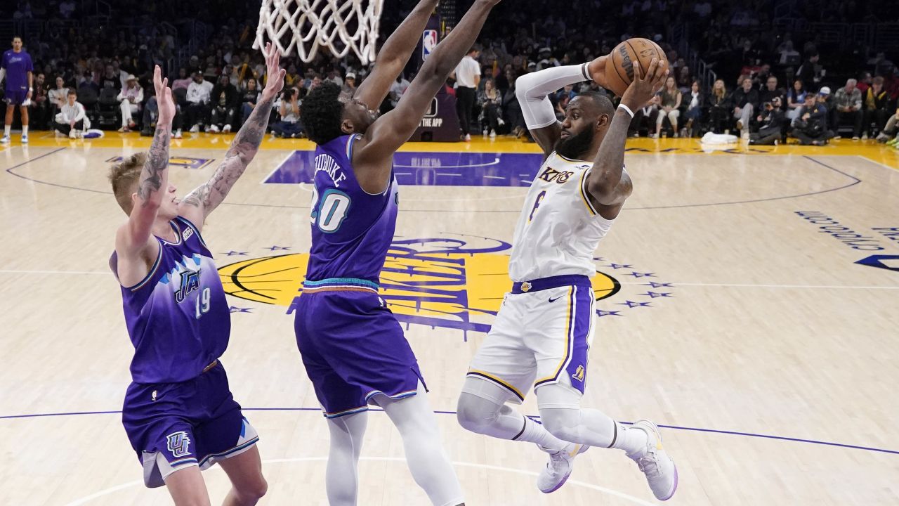 James looks to pass the ball while under pressure from two Utah Jazz defenders.