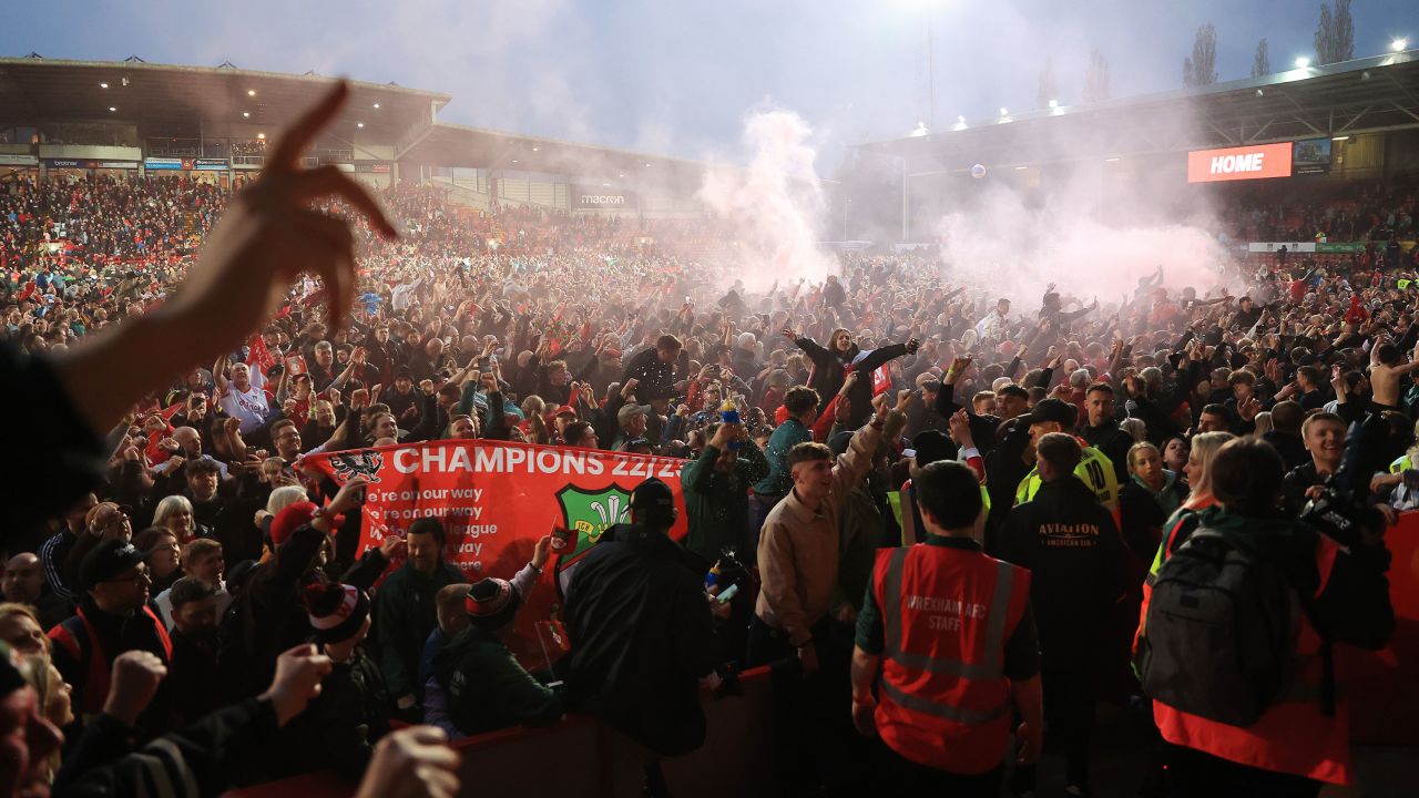 Wrexham fans celebrate on the pitch after their team beat Boreham Wood at the Racecourse Ground.