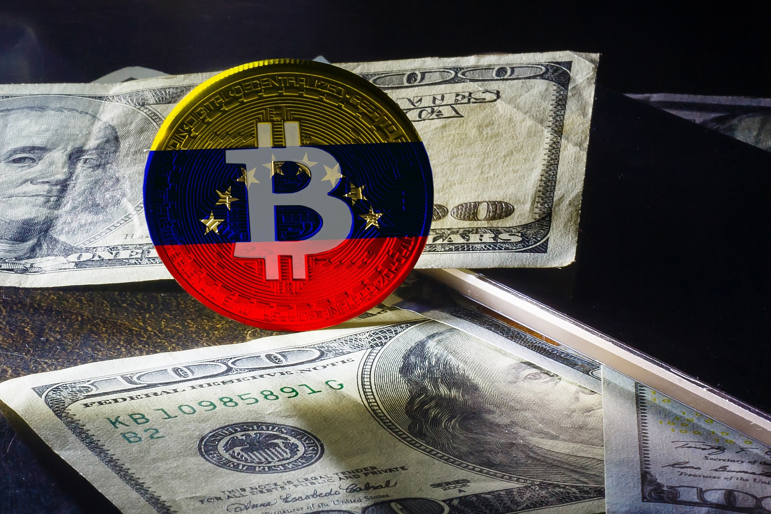 A token decorated with the Bitcoin logo and the colors of the Venezuelan flag rests next to several $100 bills.