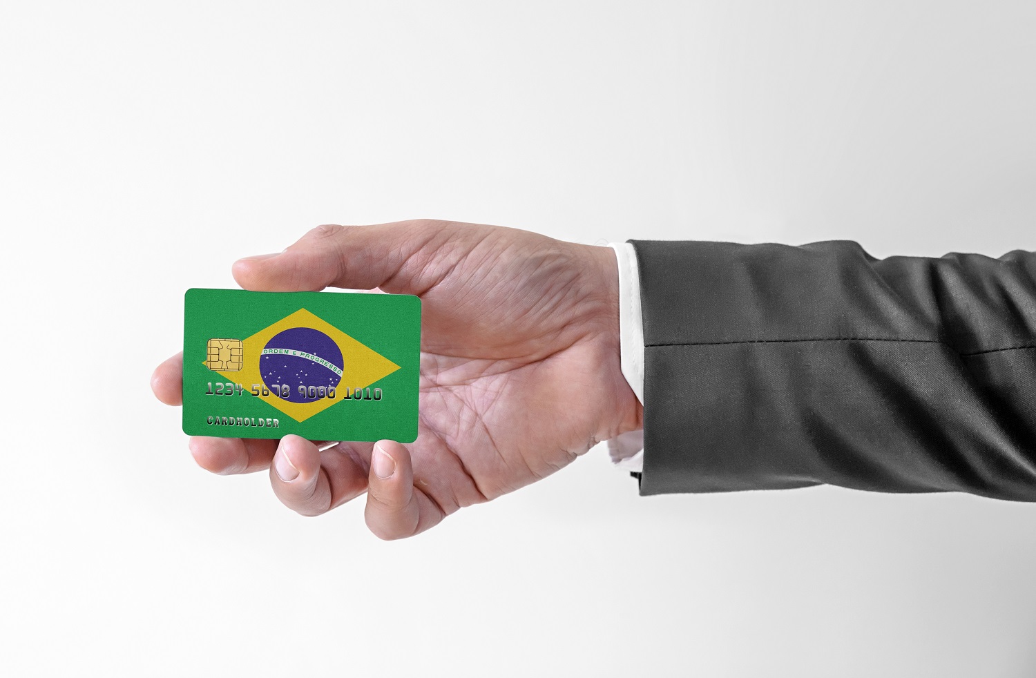 A man’s hand holds a plastic credit card decorated with the colors of the flag of Brazil.