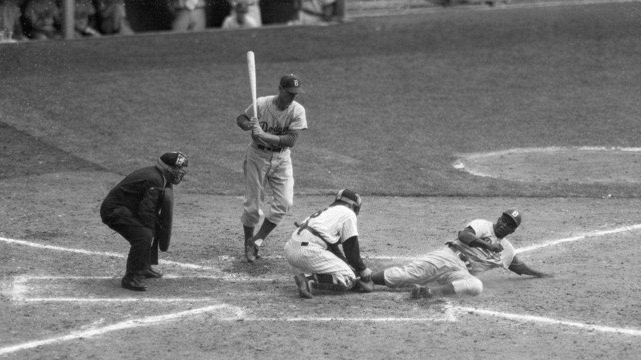 In a file photo -- September 28, 1955 -- Jackie Robinson (R) is safe under an attempted out by Yankee catcher Yogi Berra, on a steal home from third. Pinch hitter Frank Kellert (L) waits to bat. The Yankees beat the Dodgers 6-5.