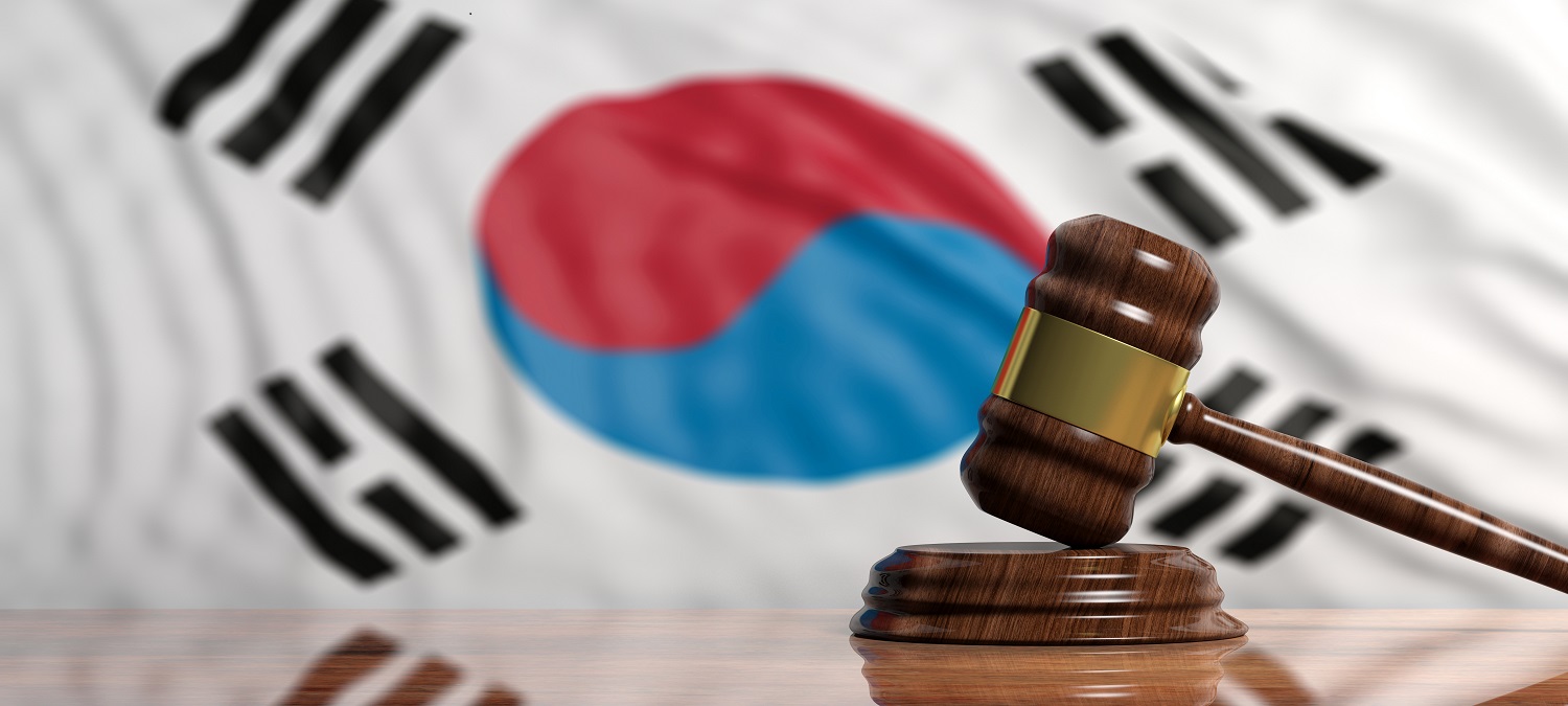 A judge’s gavel and block on a table with the South Korean flag in the background.