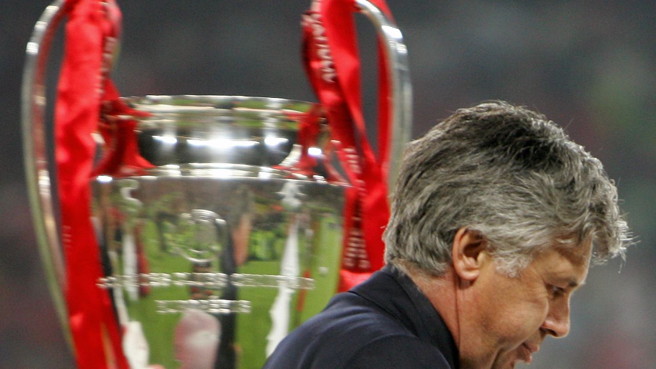 AC Milan coach Carlo Ancelotti walks past the Champions League trophy.