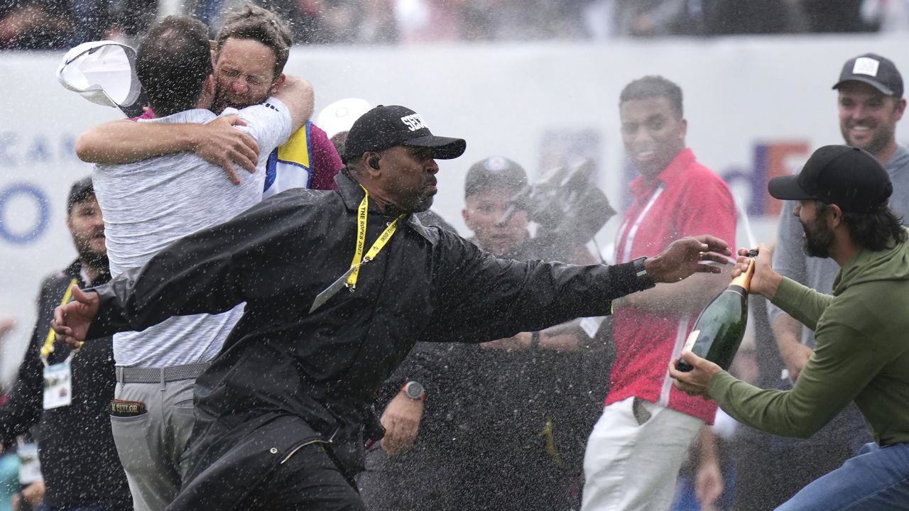 A security guard stops Hadwin as Taylor celebrates.