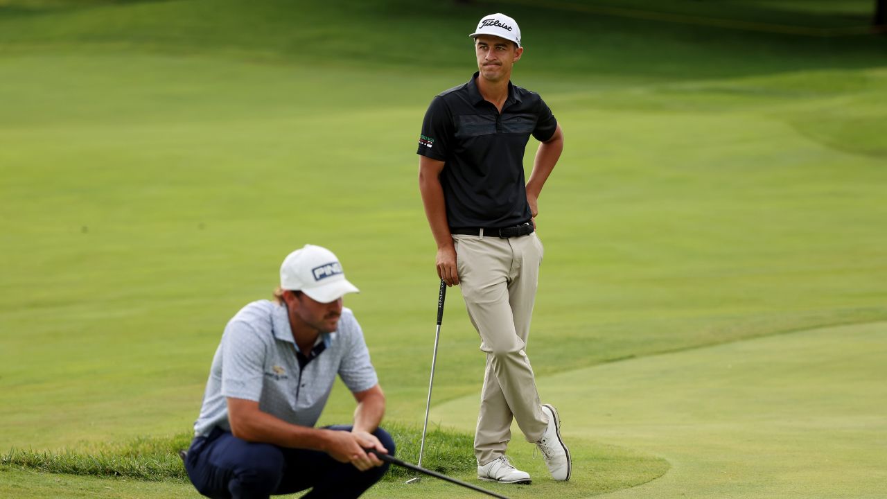 Pereira (right) waits as a competitor lines up a putt.