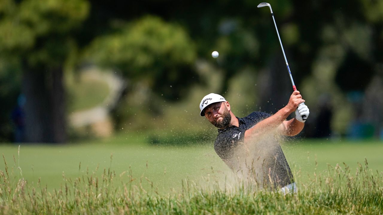 Rahm hits from a bunker during a practice round.