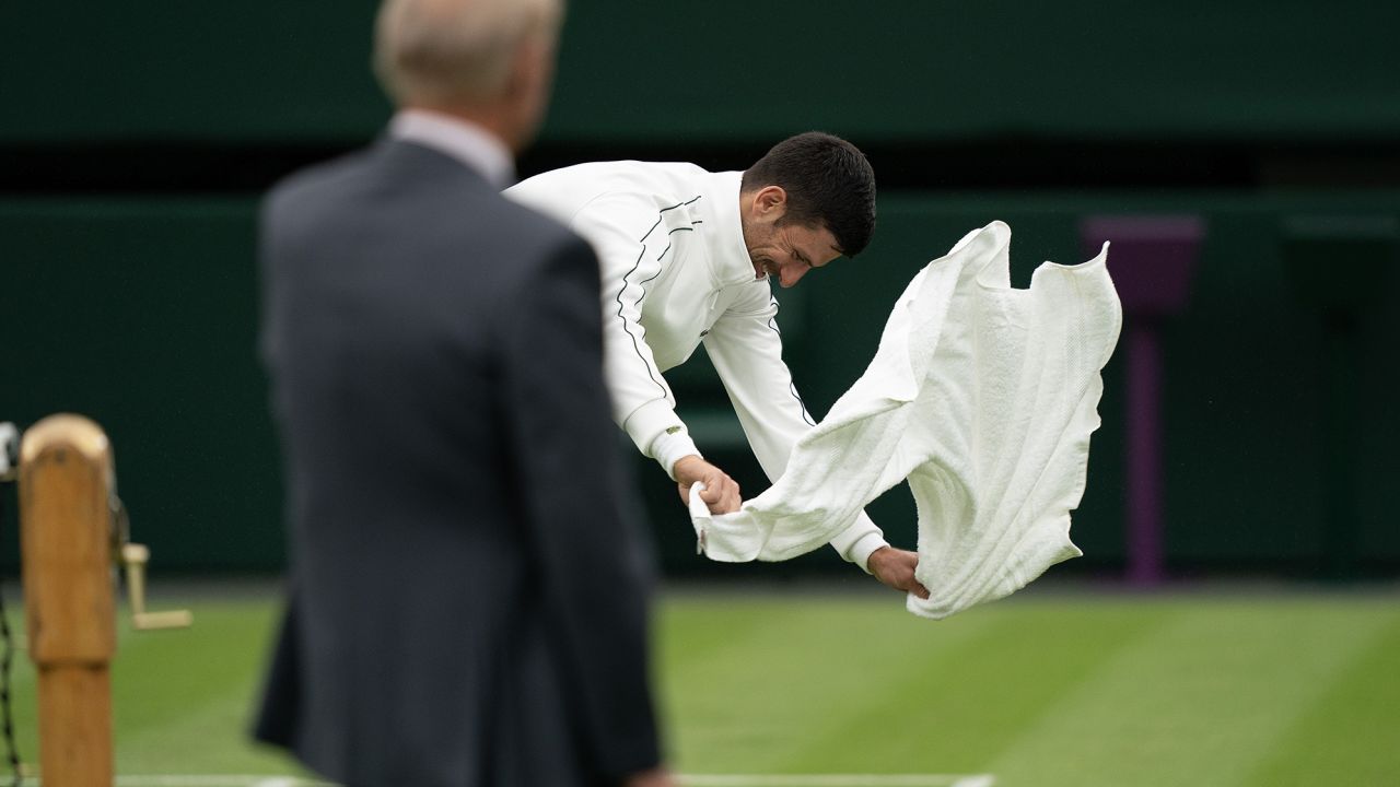 Jul 3, 2023; London, United Kingdom;  Novak Djokovic (SRB) tries drying the court dry as Referee Gerry Armstrong looks on on day one of the Wimbledon championships at the All England Lawn Tennis and Croquet Club.