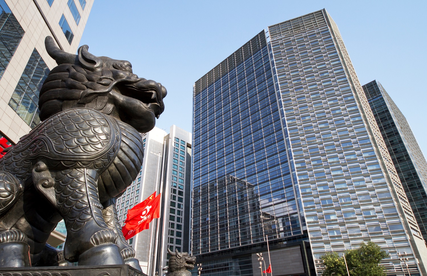 A statue of a dragon-like mythical creature outside high-rise buildings on a street in Beijing, China.