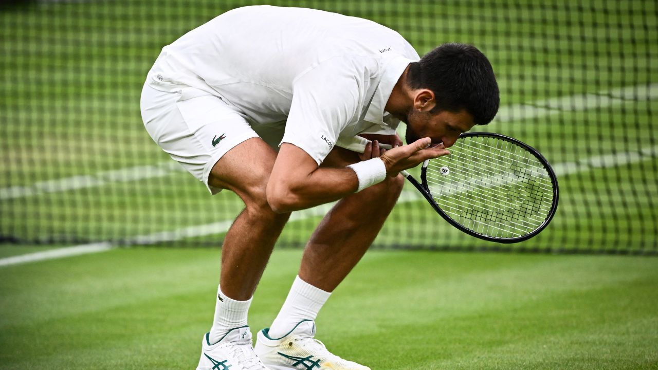 Novak Djokovic kisses the grass after beating Jannik Sinner.