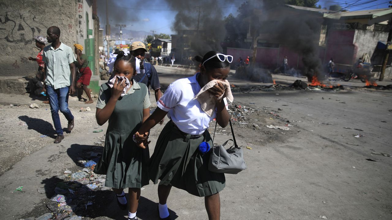 Students walk past a burning barricade that was set up by members of the police protesting bad police governance in Port-au-Prince, Haiti, Thursday, Jan. 26, 2023. (AP Photo/Odelyn Joseph)