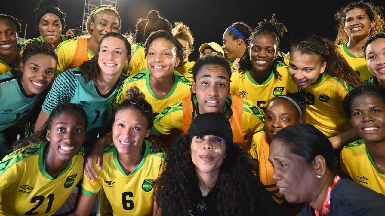 Cedella Marley (C bottom) poses with Jamaica Women's football team 'Reggae Girlz'  after the friendly football match Jamaica vs Panama at the National Stadium in Kingston, Jamaica on May 19, 2019. - In Jamaica, the spirit of Bob Marley is inescapable: it permeates the Caribbean island nation, even its football pitches -- a sign of the late reggae legend's passion for the sport. After Marley's death, his children picked up the torch -- and the country's women's team, who have qualified for their first-ever World Cup this summer in France, owe a lot to the musician's daughter Cedella. (Photo by Angela Weiss / AFP)        (Photo credit should read ANGELA WEISS/AFP via Getty Images)