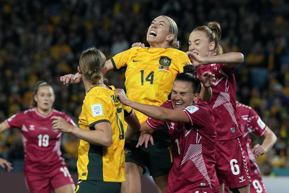 Australia's Alanna Kennedy, center, and Denmark's Karen Holmgaard, right, jump for the ball during the round of 16 match between Australia and Denmark at Stadium Australia in Sydney, Australia, on Monday, August 7.