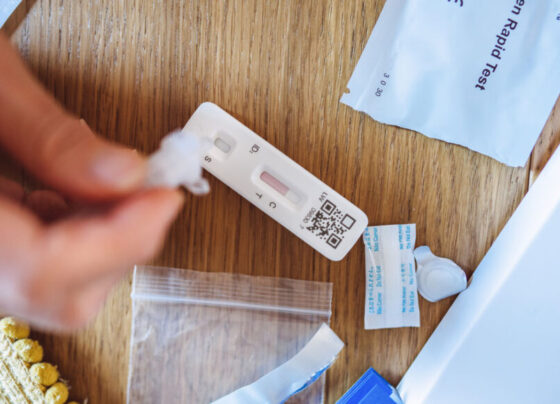 A photo of a COVID-19 test kit and a person using the test.