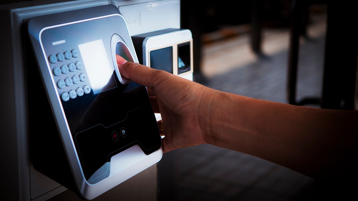 A person uses a fingerprint scanner on a security panel.