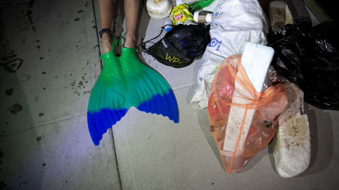 Merle Liivand sits next to a pile of trash that she picked while swimming 30 miles around Biscayne Bay wearing a mermaid tail, to create awareness on plastic pollution and climate change, in Miami Beach, Florida, U.S. April 15, 2023.