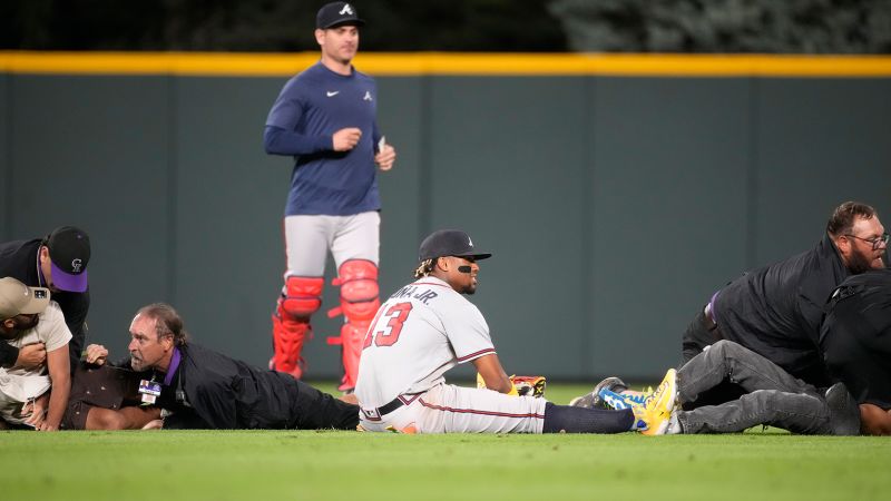 Atlanta Braves’ Ronald Acuña Jr. knocked to the ground after two fans run onto Coors Field