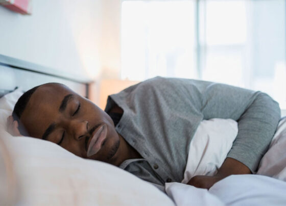 A photo of a black man sleeping on his side facing the camera.