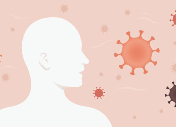 An illustration of a person's head in profile while illustrated germs float around them on a pink background.