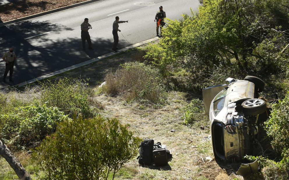 Law enforcement officers investigate the scene of Woods' rollover crash in Rancho Palos Verdes, California, in February 2021. Woods <a href="https://www.cnn.com/2021/04/07/us/tiger-woods-update-crash-cause/index.html" target="_blank">suffered serious leg injuries</a> in the one-car accident and had to be pulled from his vehicle by emergency responders.