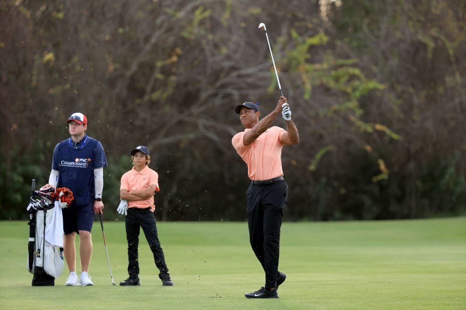 Woods plays a shot at the PNC Championship as his son, Charlie, watches in December 2021. It was Tiger's first time competing since the car crash, and he used a golf cart to get around the course. He and Charlie <a href="https://www.cnn.com/2021/12/18/sport/tiger-woods-pnc-championship/index.html" target="_blank">finished in second place.</a> "I'm a long way away from playing tournament golf," Tiger said. "This is hit, hop in a cart."