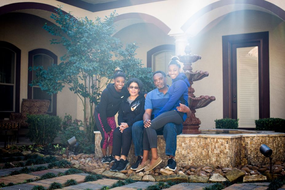 Biles, left, poses at home with her grandparents Ron and Nellie, who adopted her and her younger sister Adria, right.