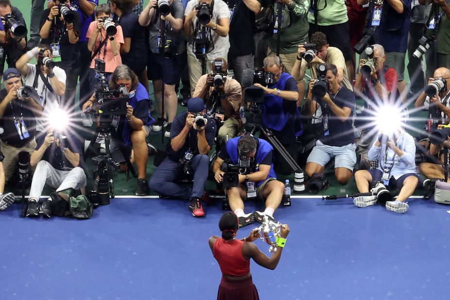 Gauff holds her trophy in front of gathered photographers after her victory.