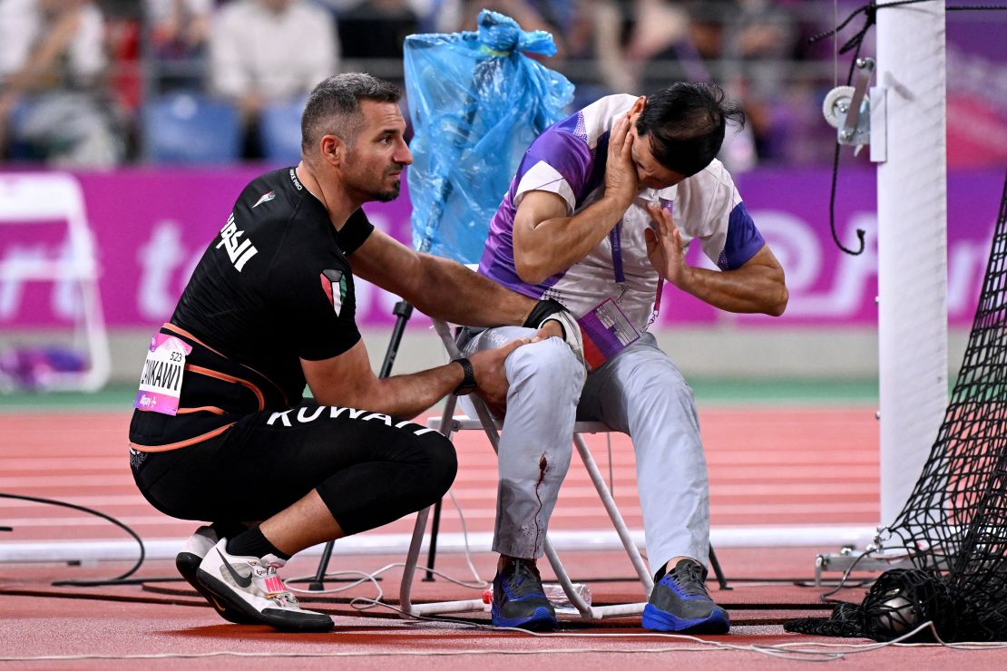 In this picture taken on September 30, 2023, an official reacts in pain after his leg was injured by a stray hammer thrown by Ali Zankawi (L) who attempts to stem the bleeding during the men's hammer throw final athletics event at the 2022 Asian Games in Hangzhou in China's eastern Zhejiang province.