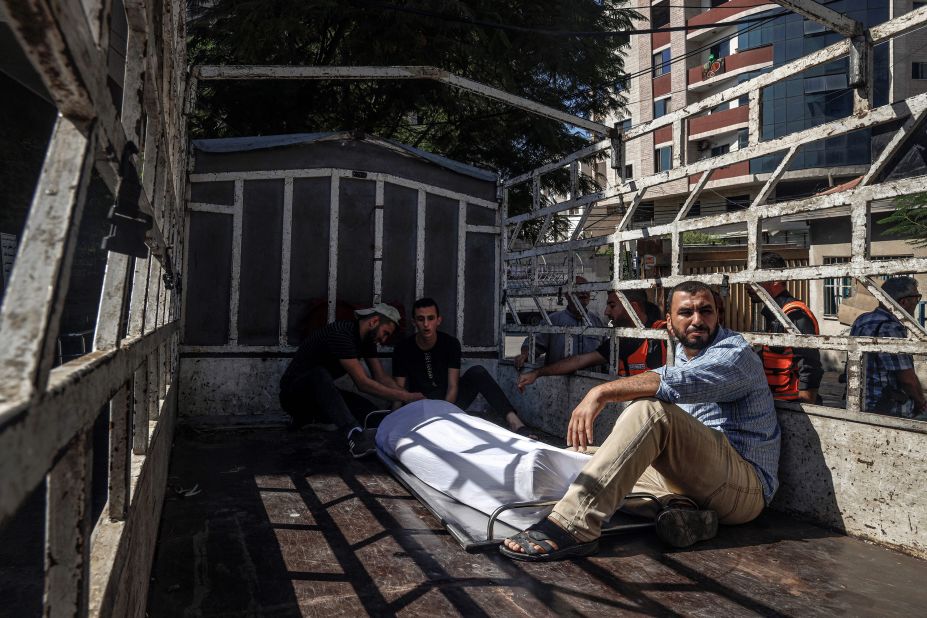 Outside of a hospital in Gaza, men sit next to the covered body of a Palestinian militant killed during Saturday's clashes.