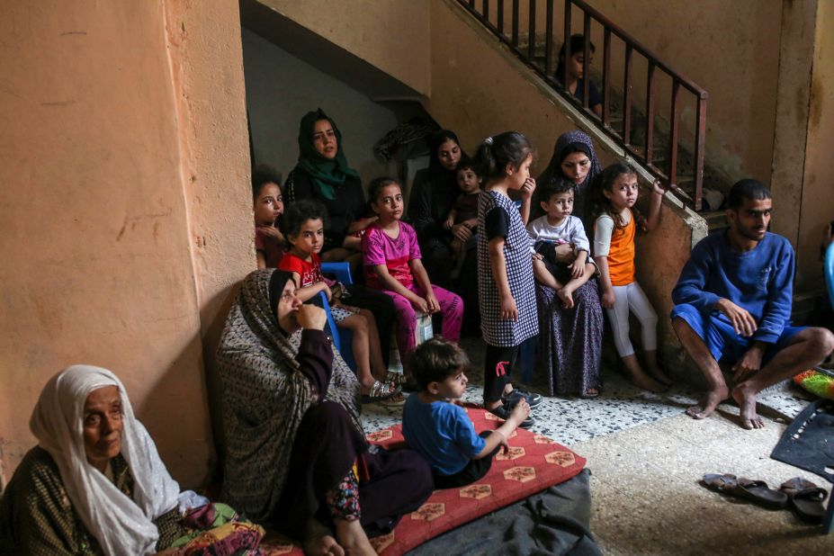 A family takes shelter at a neighbor's house after their home was damaged in an Israeli airstrike in the Shati refugee camp in Gaza on October 9.