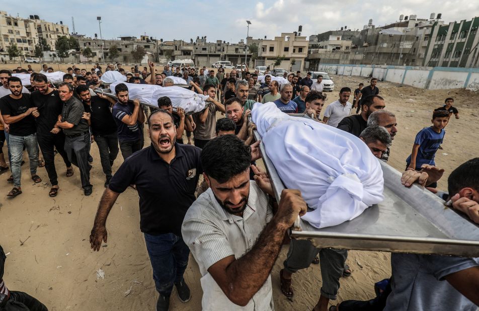 People carry bodies of Palestinians killed during an Israeli airstrike prior to their burial in Khan Younis, Gaza, on Wednesday, October 11.