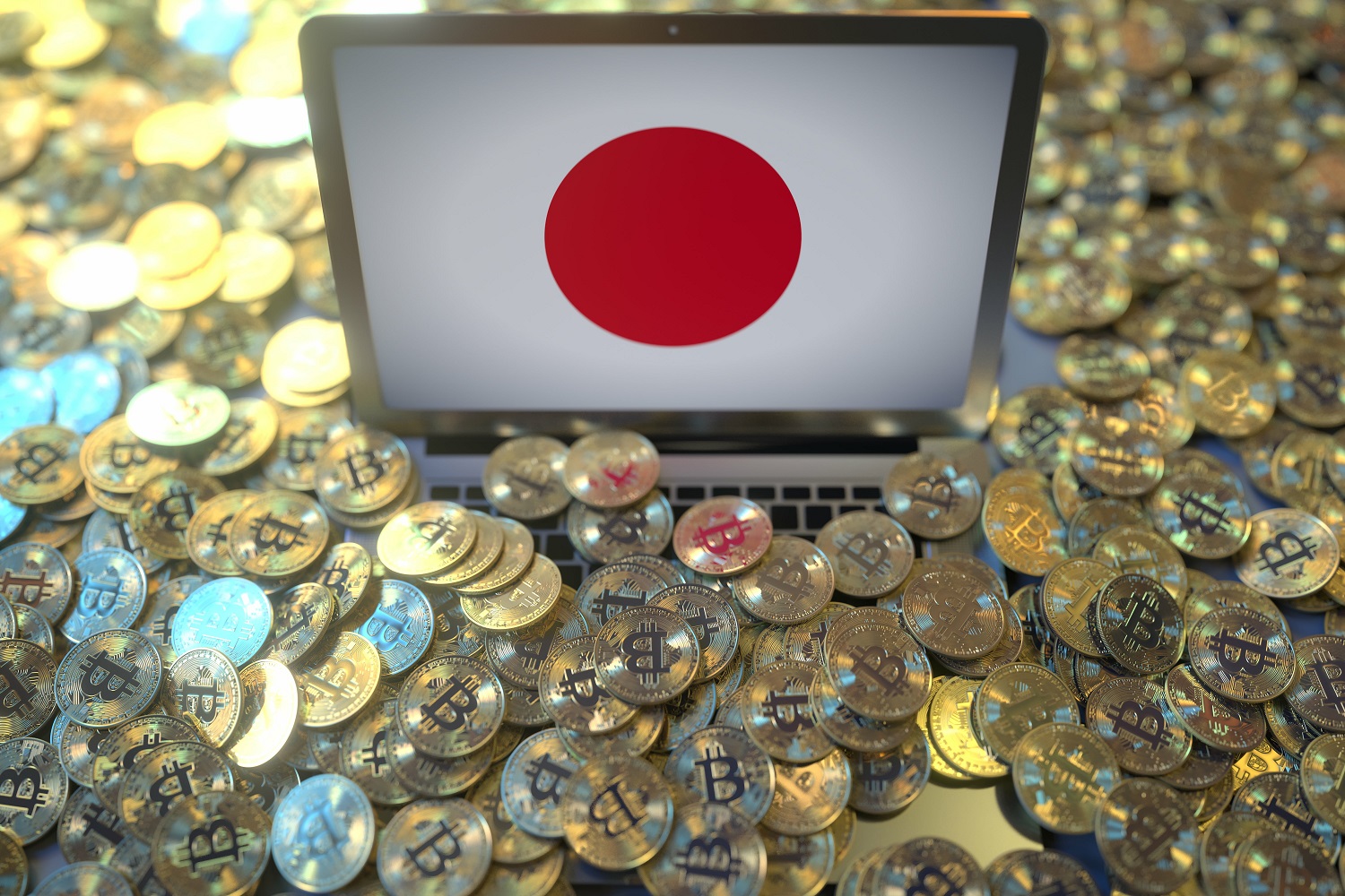 A large number of gold-colored metal tokens intended to represent Bitcoins scattered around a laptop computer whose screen displays the Japanese flag.