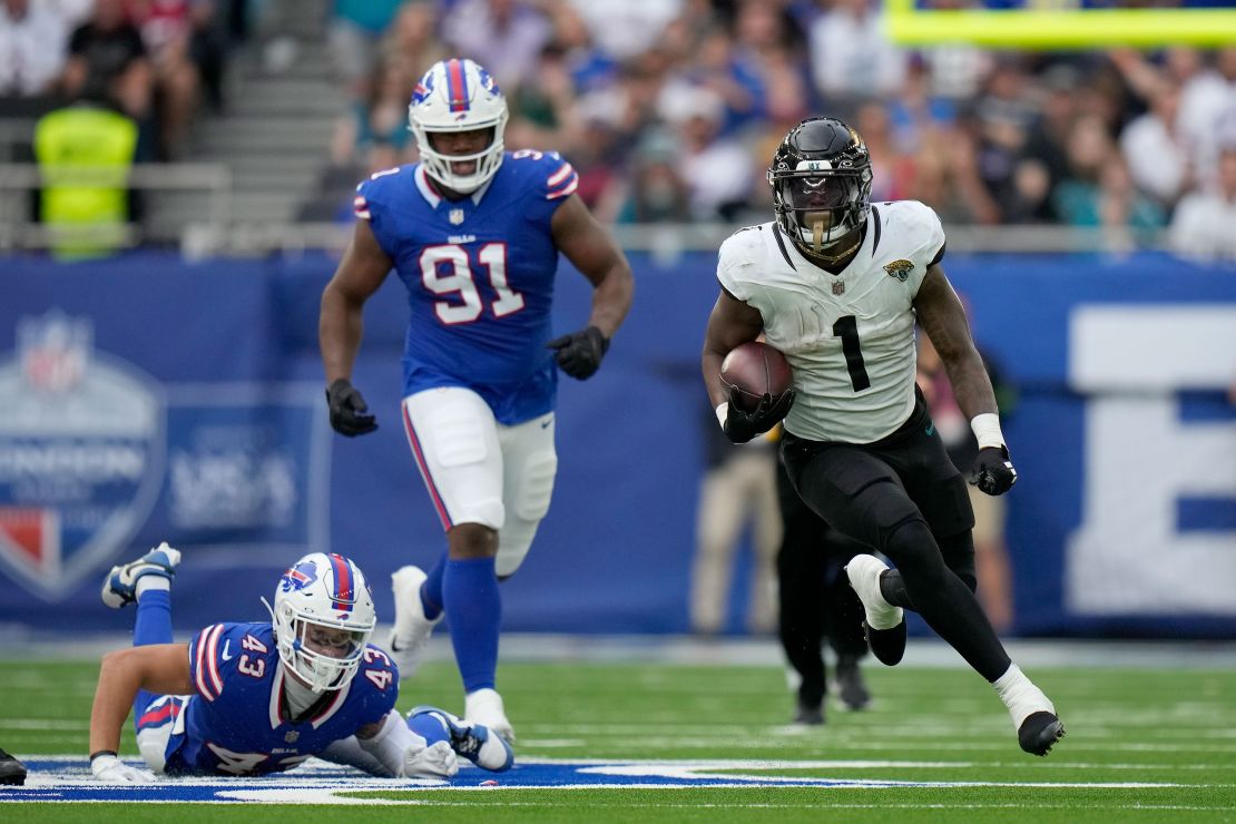 Jacksonville Jaguars running back Travis Etienne Jr. (1) gets away from Buffalo Bills linebacker Terrel Bernard (43) and Buffalo Bills defensive tackle Ed Oliver (91) during an NFL football game between Jacksonville Jaguars and Buffalo Bills at the Tottenham Hotspur stadium in London, Sunday, Oct. 8, 2023. (AP Photo/Alastair Grant)