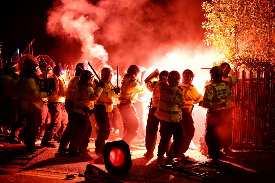 Police officers battle with flares let off by Legia fans ahead of the game at Villa Park.