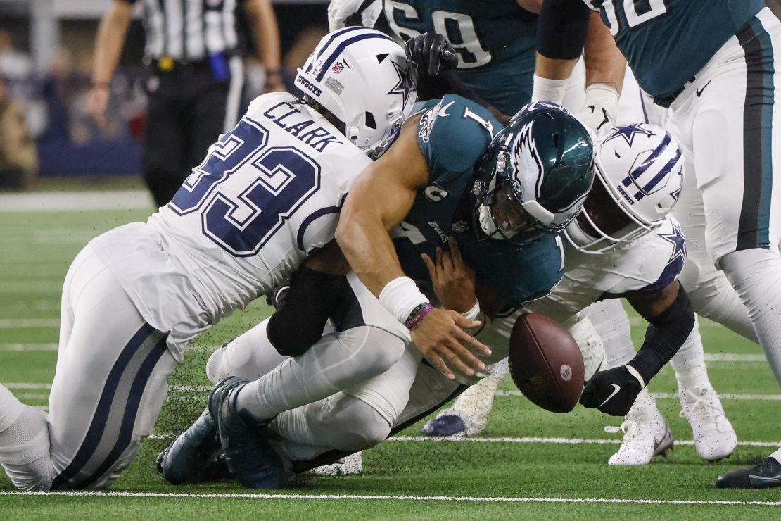 Dallas Cowboys safety Donovan Wilson, right, forces a fumble by Philadelphia Eagles quarterback Jalen Hurts, center, as teammate Damone Clark (33) helps apply pressure during the first half of an NFL football game, Sunday, Dec. 10, 2023, in Arlington, Texas. The Cowboys recovered the ball on the play. (AP Photo/Michael Ainsworth)