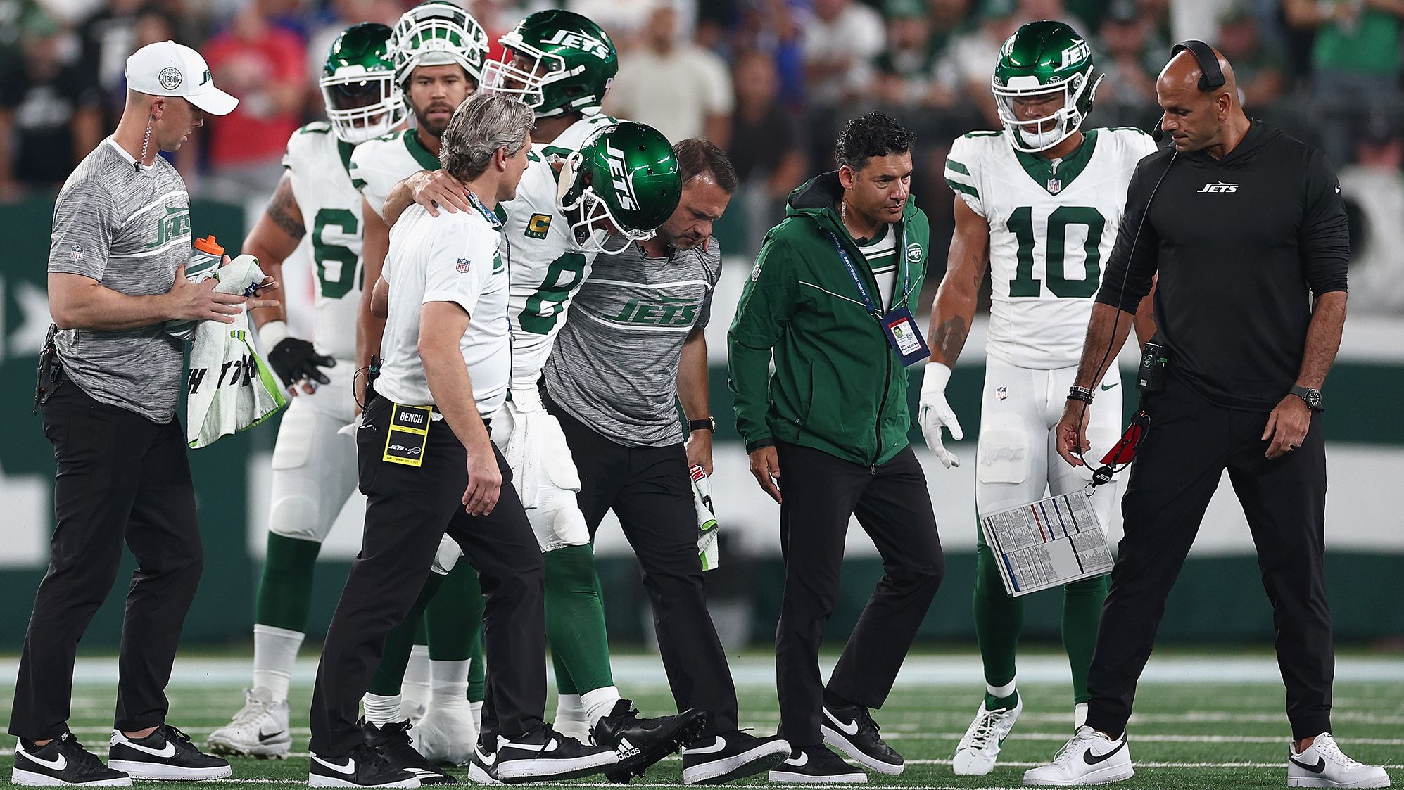 EAST RUTHERFORD, NEW JERSEY - SEPTEMBER 11: Quarterback Aaron Rodgers #8 of the New York Jets is helped off the field by team trainers after an injury during the first quarter of the NFL game against the Buffalo Bills at MetLife Stadium on September 11, 2023 in East Rutherford, New Jersey. (Photo by Elsa/Getty Images)