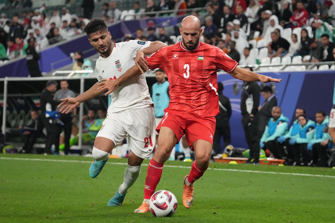 AL RAYYAN, QATAR - JANUARY 14: Mohammed Rashid of Palestine and Mohammad Mohebbi of Iran compete for the ball during the AFC Asian Cup Group C match between Iran and Palestine at Education City Stadium on January 14, 2024 in Al Rayyan, Qatar. (Photo by Masashi Hara/Getty Images)