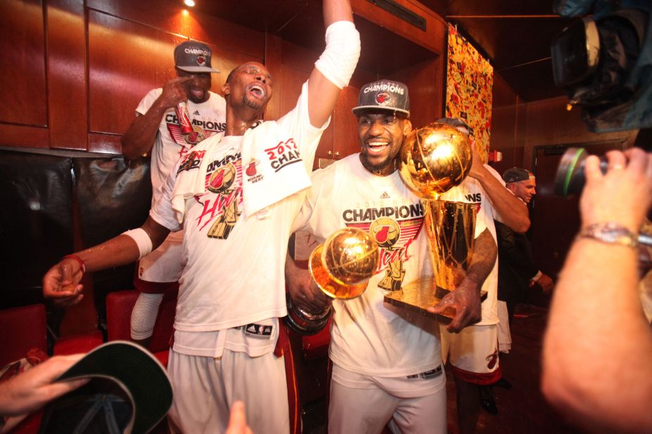 James celebrates with teammates after the Heat won the 2012 NBA Finals. James is holding the Larry O'Brien Championship Trophy, right, and the Bill Russell Finals MVP Award.