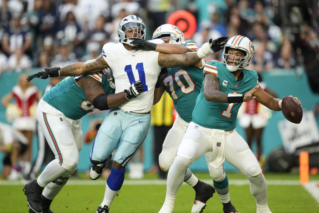 Miami Dolphins quarterback Tua Tagovailoa stands back to pass as Dallas Cowboys linebacker Micah Parsons is held back by Miami's offensive line on Christmas Eve 2023.