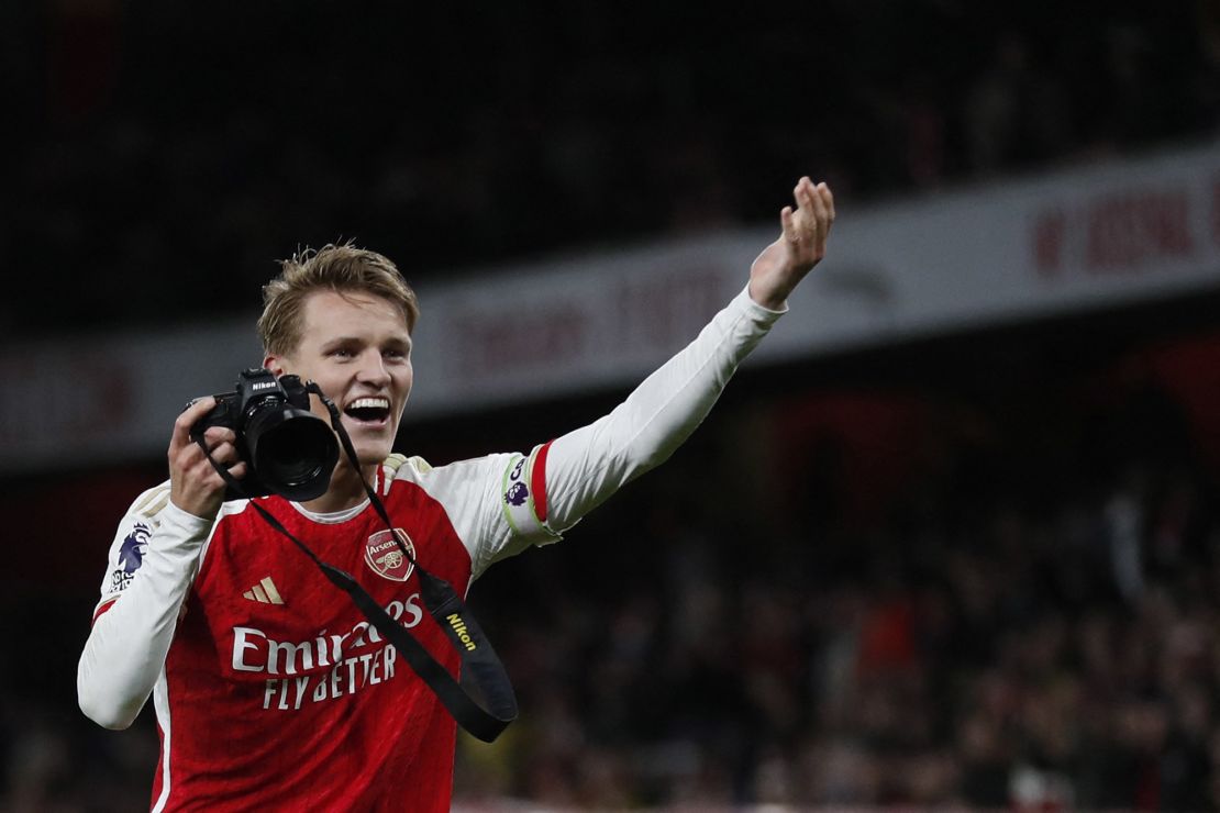 Arsenal's Martin Ødegaard takes pictures as he celebrates at the end of the Premier League match.