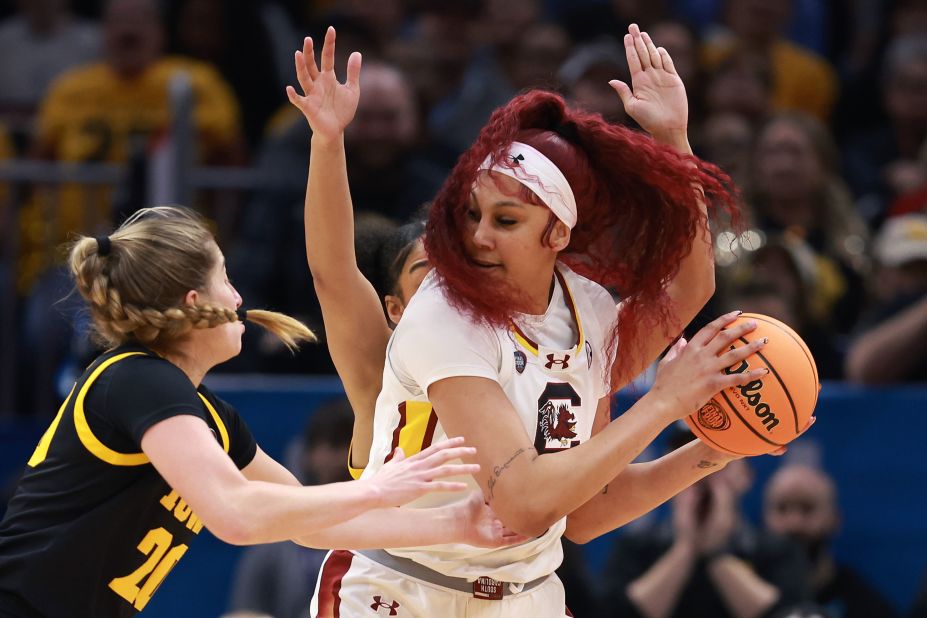 South Carolina's Cardoso keeps the ball away from Martin and Stuelke of the Iowa Hawkeyes.