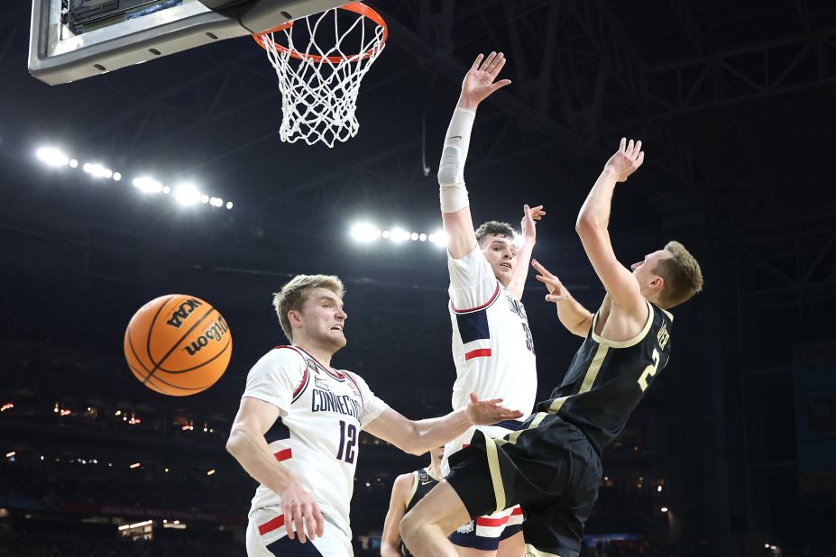 Purdue's Fletcher Loyer loses control of the ball while being guarded by UConn's Cam Spencer and Donovan Clingan.