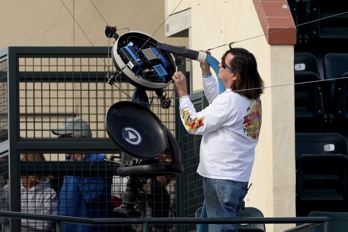 Beekeeper Lance Davis removes bees from an overhead camera during the delay.