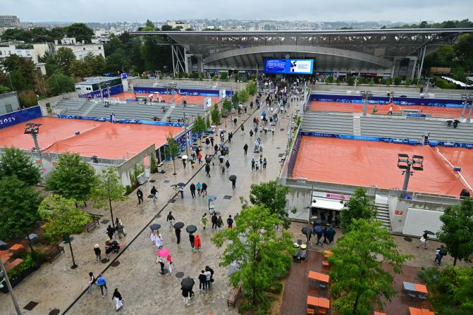 Spectators at the Roland Garros Stadium take shelter from the rain as wet weather delays the start of tennis play on July 27.