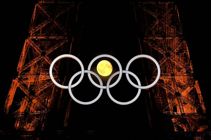 The moon is seen through the Olympic rings on the Eiffel Tower on Tuesday, July 23.