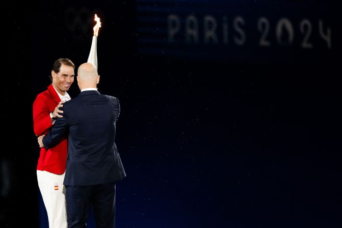 French soccer icon Zinedine Zidane, right, hands off the Olympic torch to Rafael Nadal, <a href="https://www.cnn.com/sport/live-news/paris-olympics-2024-opening-ceremony-seine#h_249177297f865db4aab2621e59ee0965">the Spanish tennis star</a> who has won two Olympic gold medals and a record 14 French Opens. The torch passed to various athletes before ending up with Riner and Pérec.