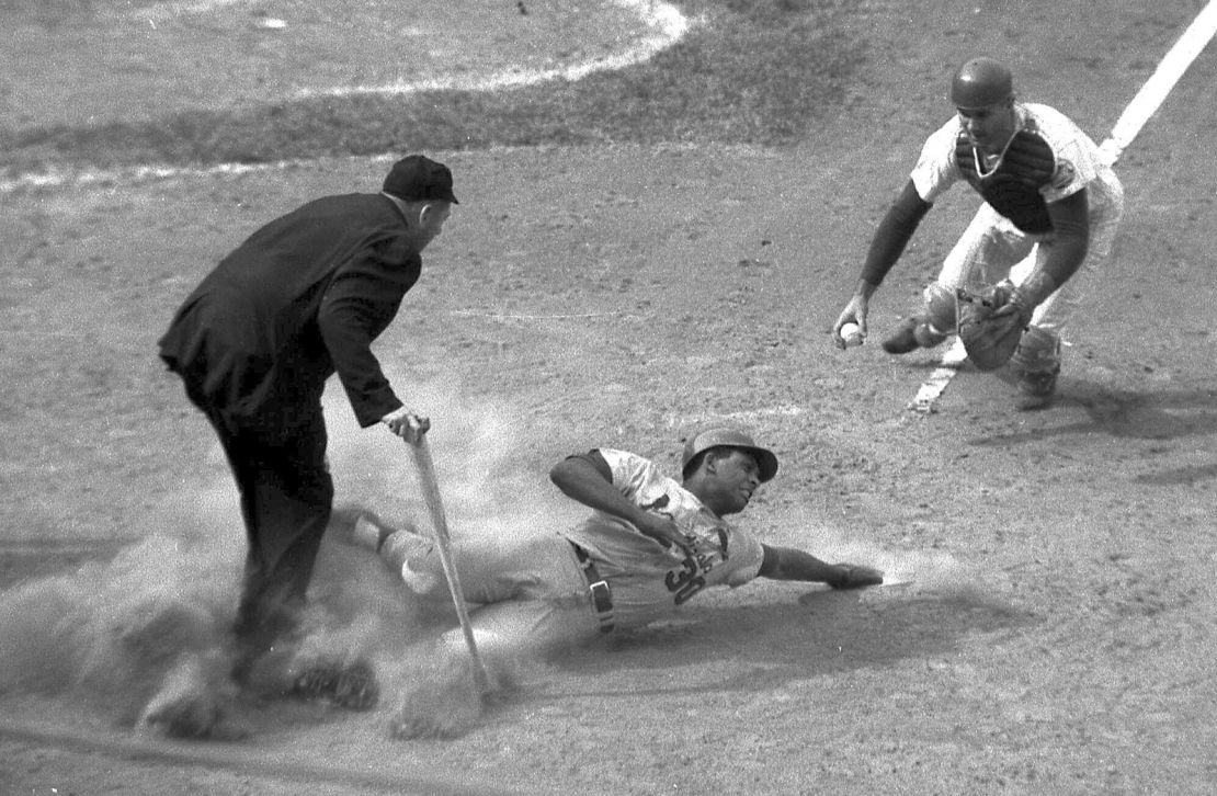 St. Louis Cardinals' Orlando Cepeda scores in the eighth inning of a baseball game as New York Mets catcher J.C. Martin, right, and umpire Tim McCarver, left, watch at Shea Stadium in New York in 1968.